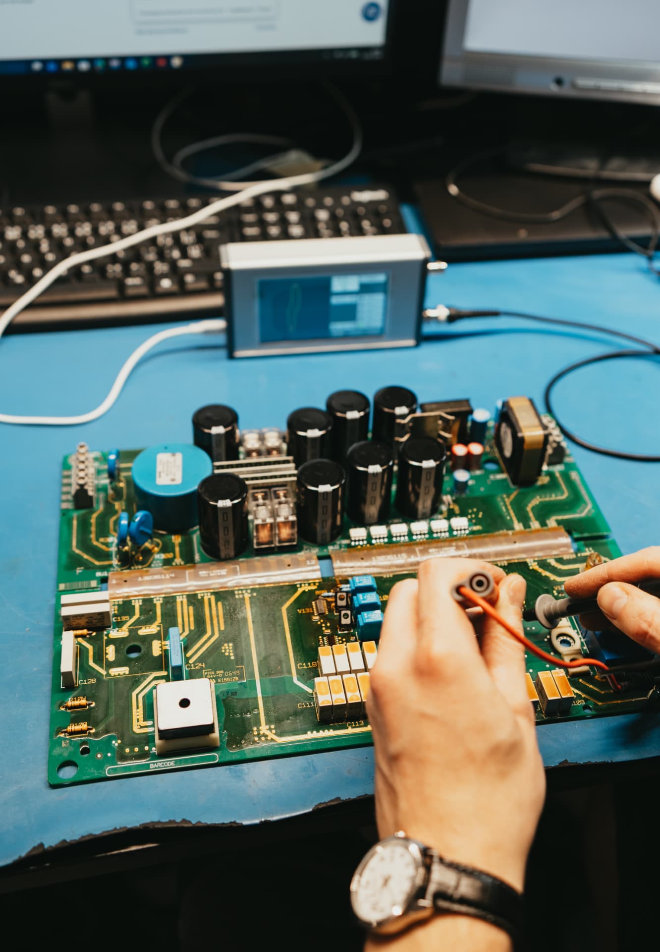 Techniker misst Bauteile auf der Leistungsplatine eines Frequenzumrichters